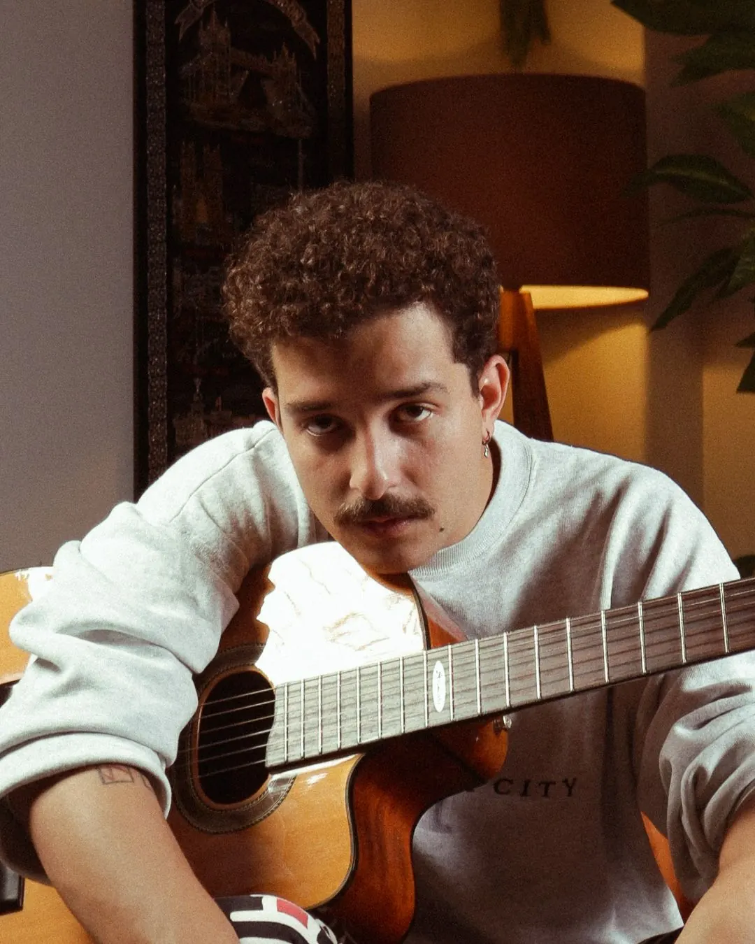 Músico com violão olhando para a câmera
