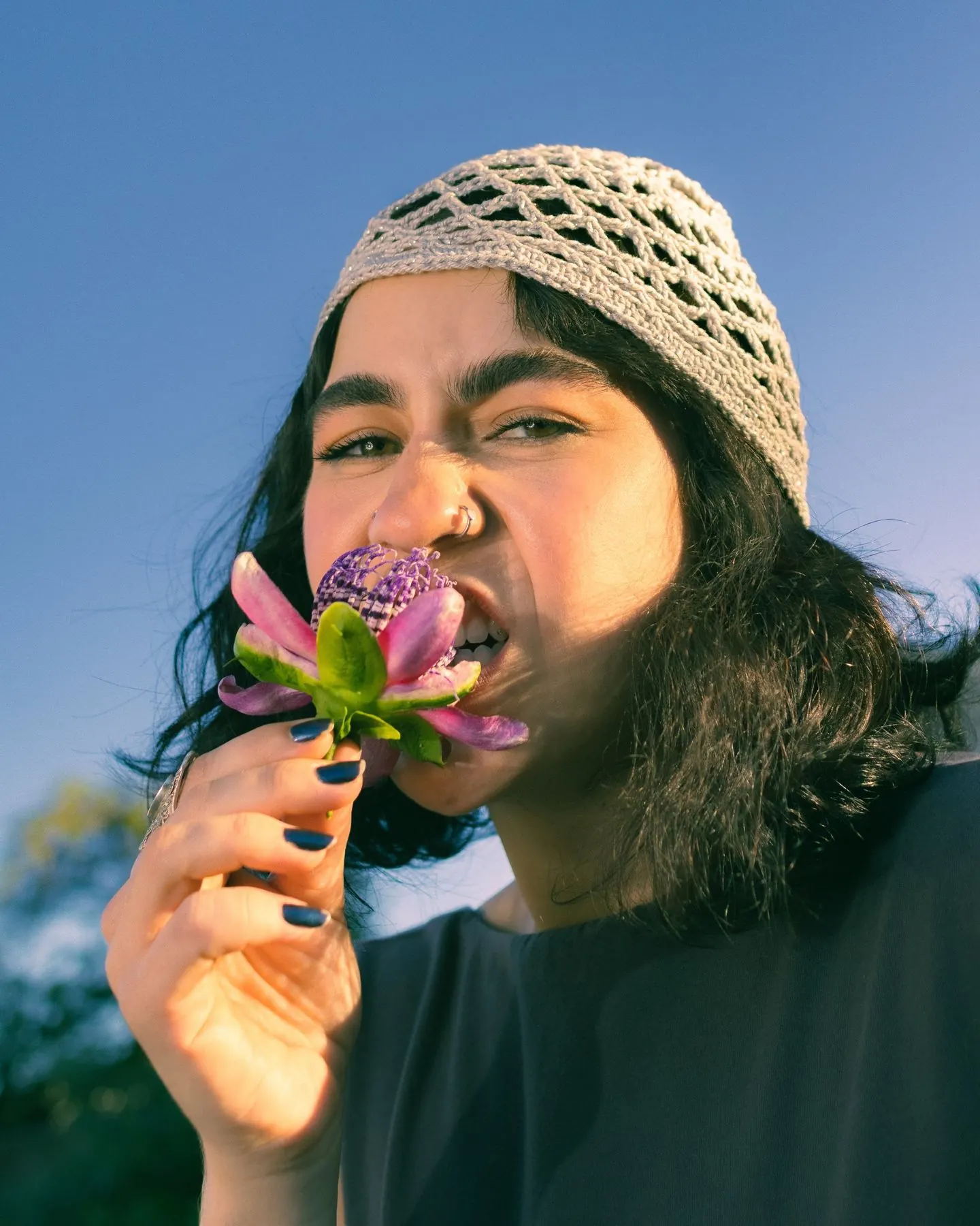 Moça de touca de crochê mordendo uma flor de maracujá