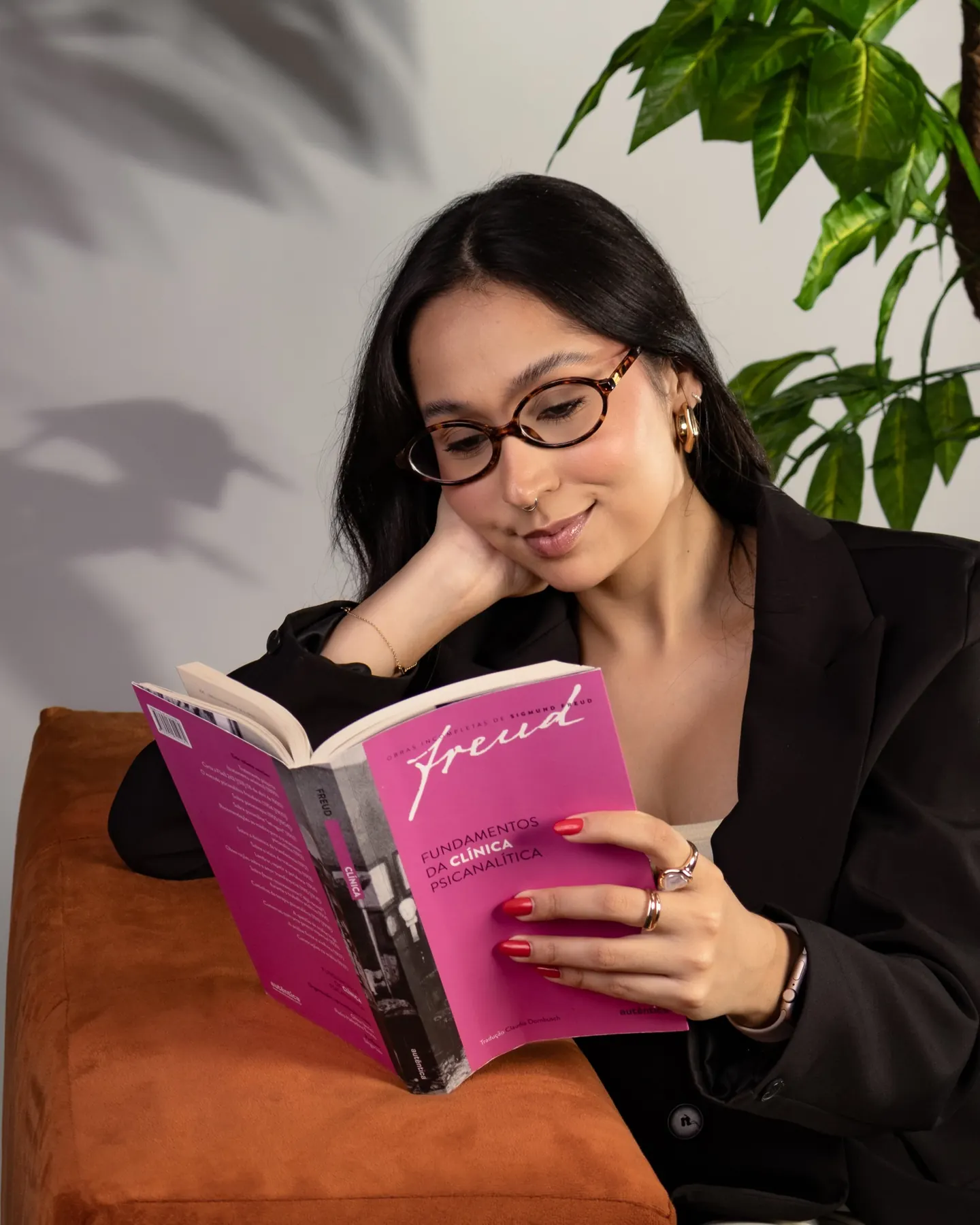 Psicóloga de óculos sentada lendo um livro de psicanálise